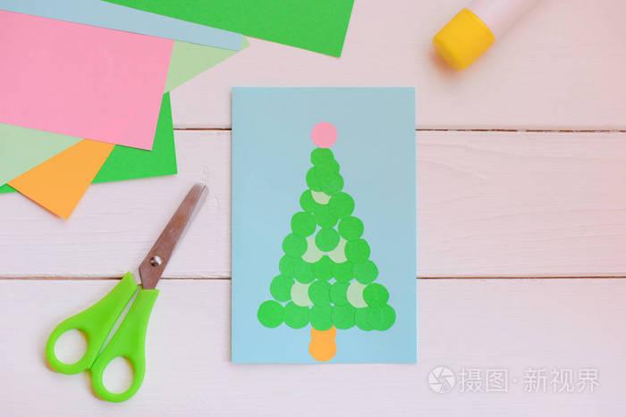 用简单几何形状的纸制圣诞贺卡彩色纸套剪刀木桌上的胶棒.
