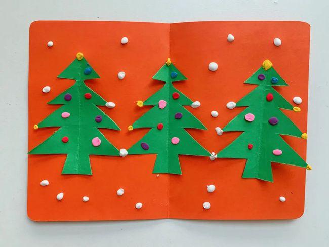 第四步把圣诞树粘在橙色的备用贺卡里面在用白色的粘土点缀空白的