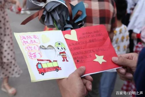 小朋友们将自己的鲜花和手绘贺卡送给消防员.